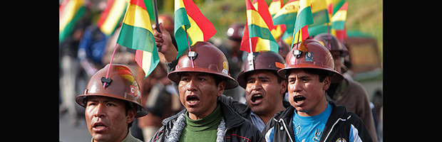 Mineros marchando con la bandera de Bolivia en su casco