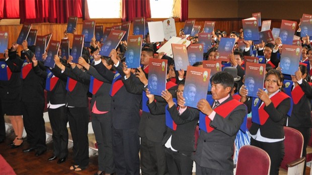 La imagen muestra a los graduados manteniendo en alto sus títulos profesionales.